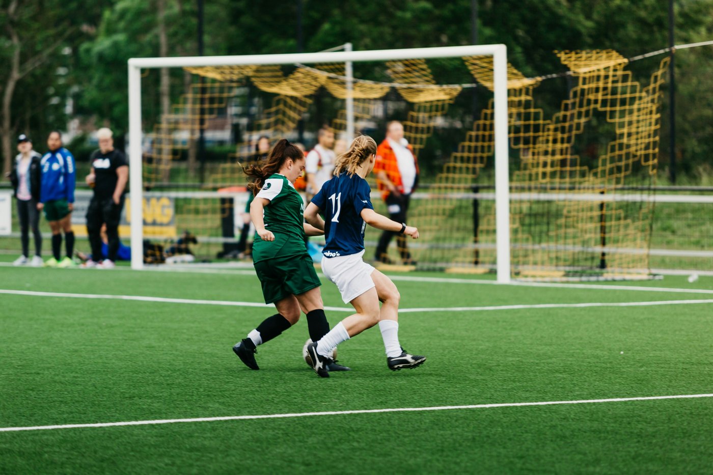 Joueuse du club en bleu au duel avec une adversaire en vert